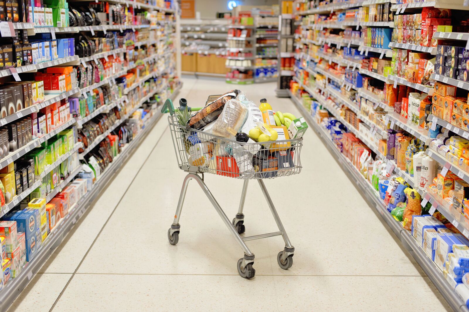 Full shopping cart in supermarket aisle