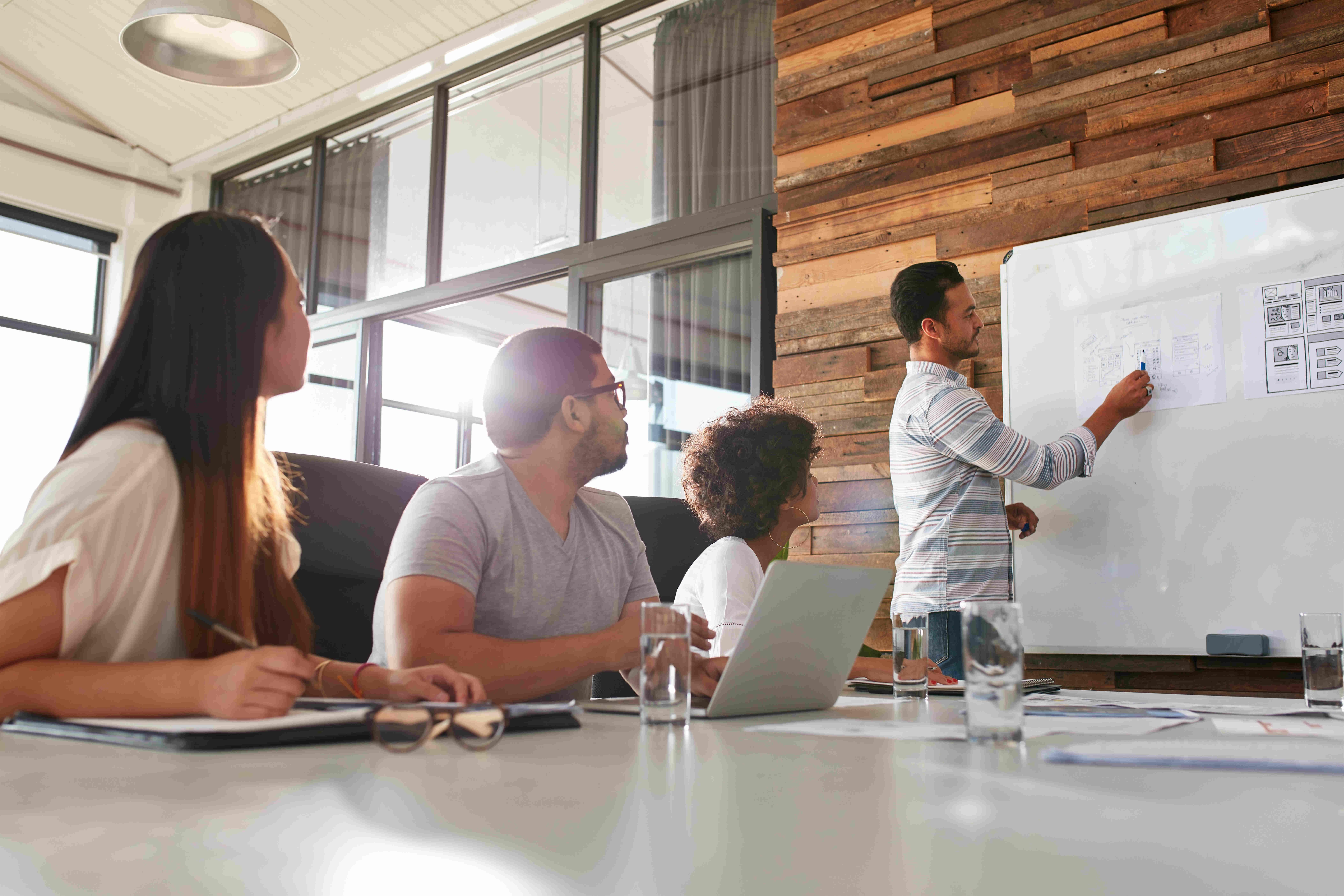 Shot of a male office worker giving creative presentation to his colleagues. Businessman explaining business plan to coworkers in conference room.