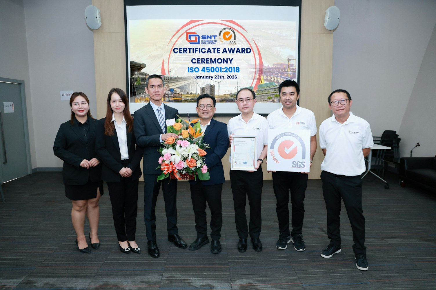 SGS representative presenting a congratulatory flower basket with the ISO 45001:2018 certificate to SNT Concrete Solution’s management team