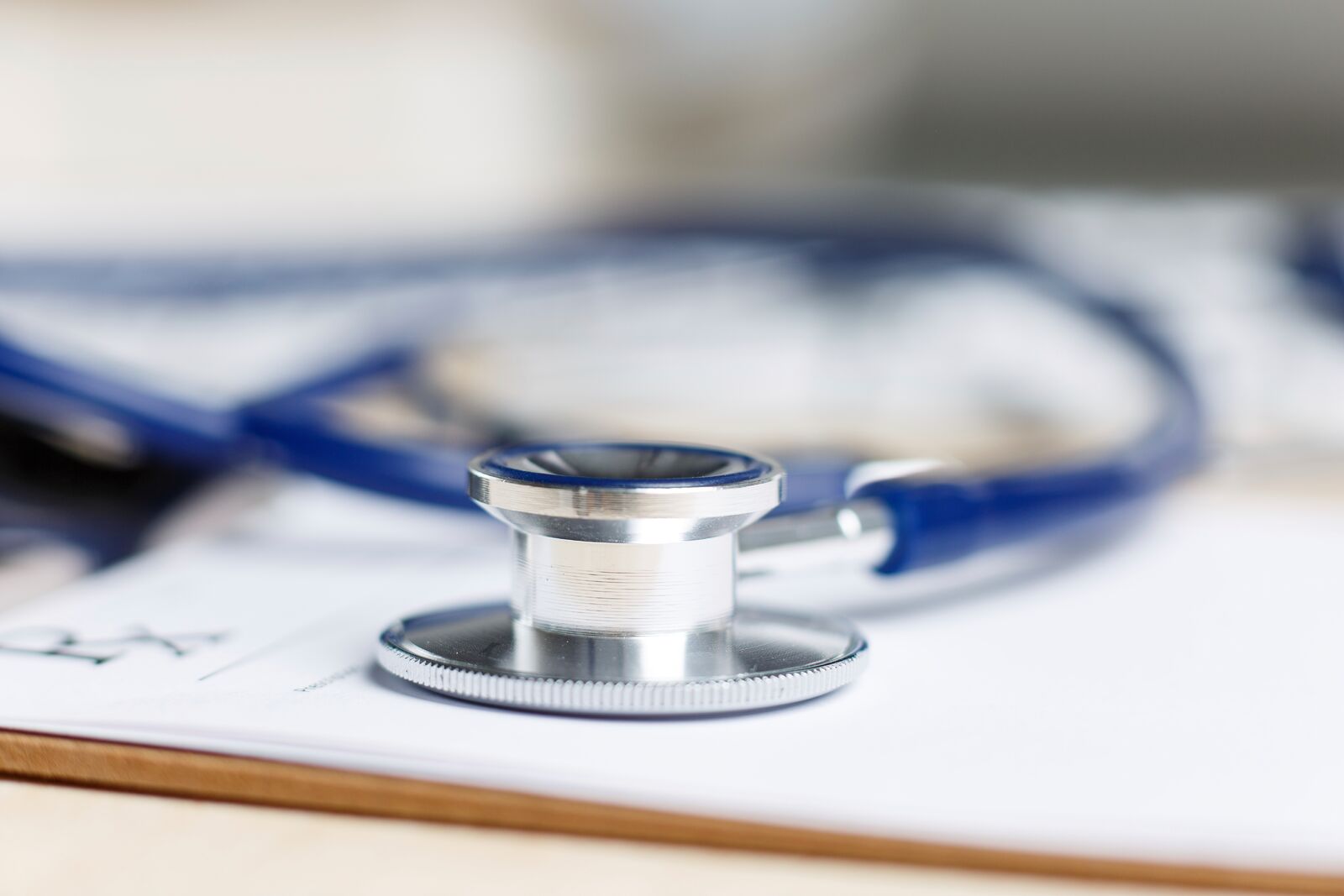 Prescription form clipped to pad lying on table with stethoscope. Medicine or pharmacy concept. Empty medical form ready to be used