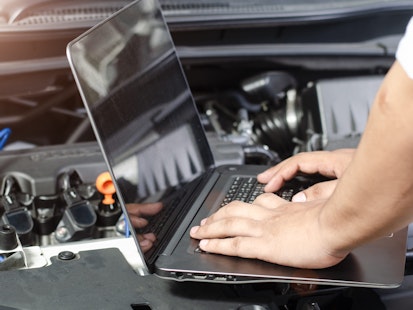 Diagnostic automobile avec ordinateur portable sur moteur ouvert Mécanicien utilisant un ordinateur portable pour diagnostiquer un moteur de voiture.