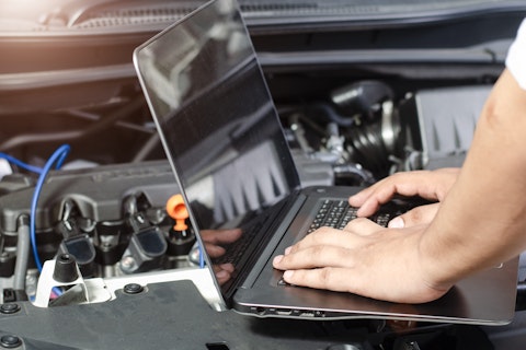Mécanicien utilisant un ordinateur portable pour diagnostiquer un moteur de voiture.