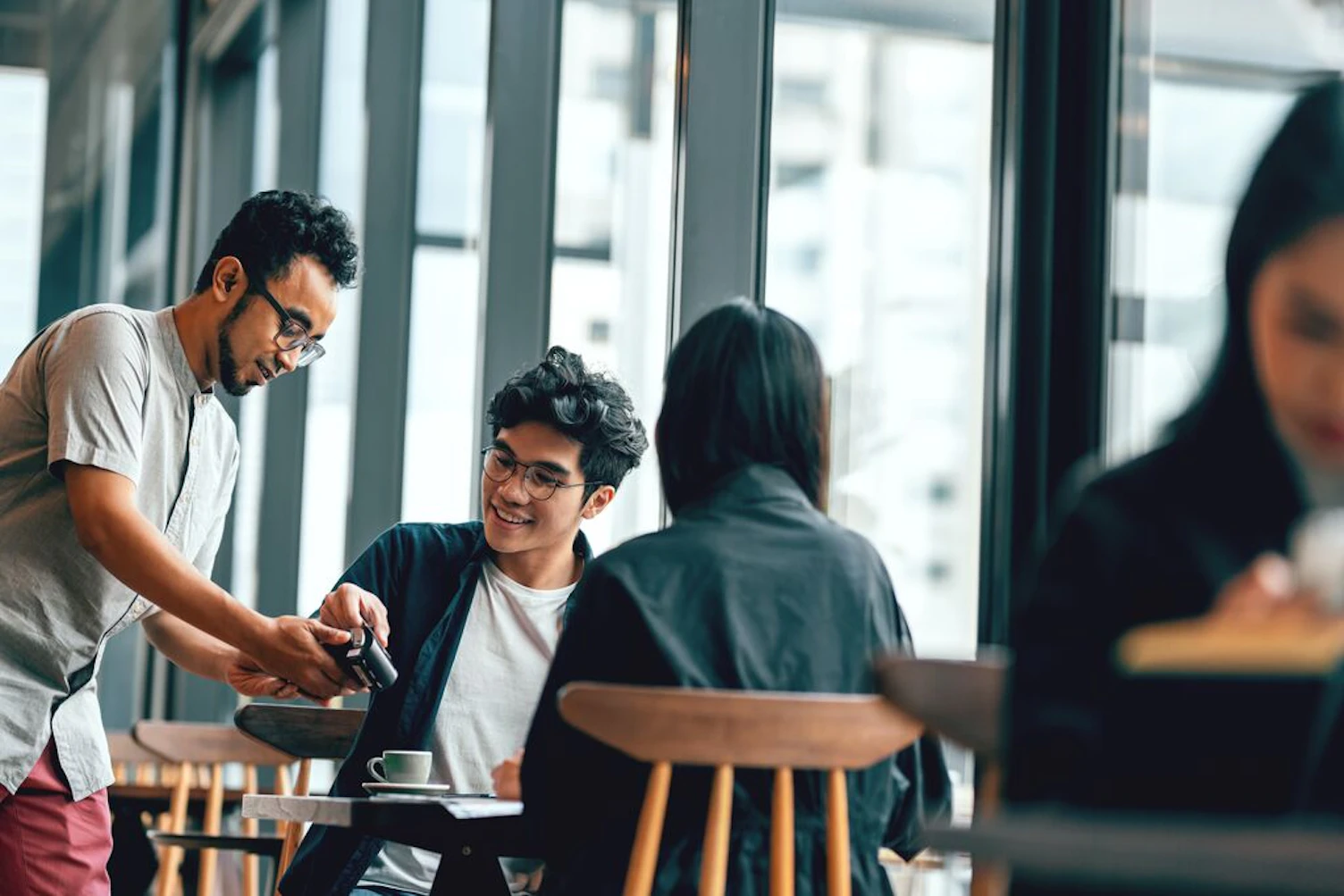 Couple in a Cafe Paying with Mobile Phone
