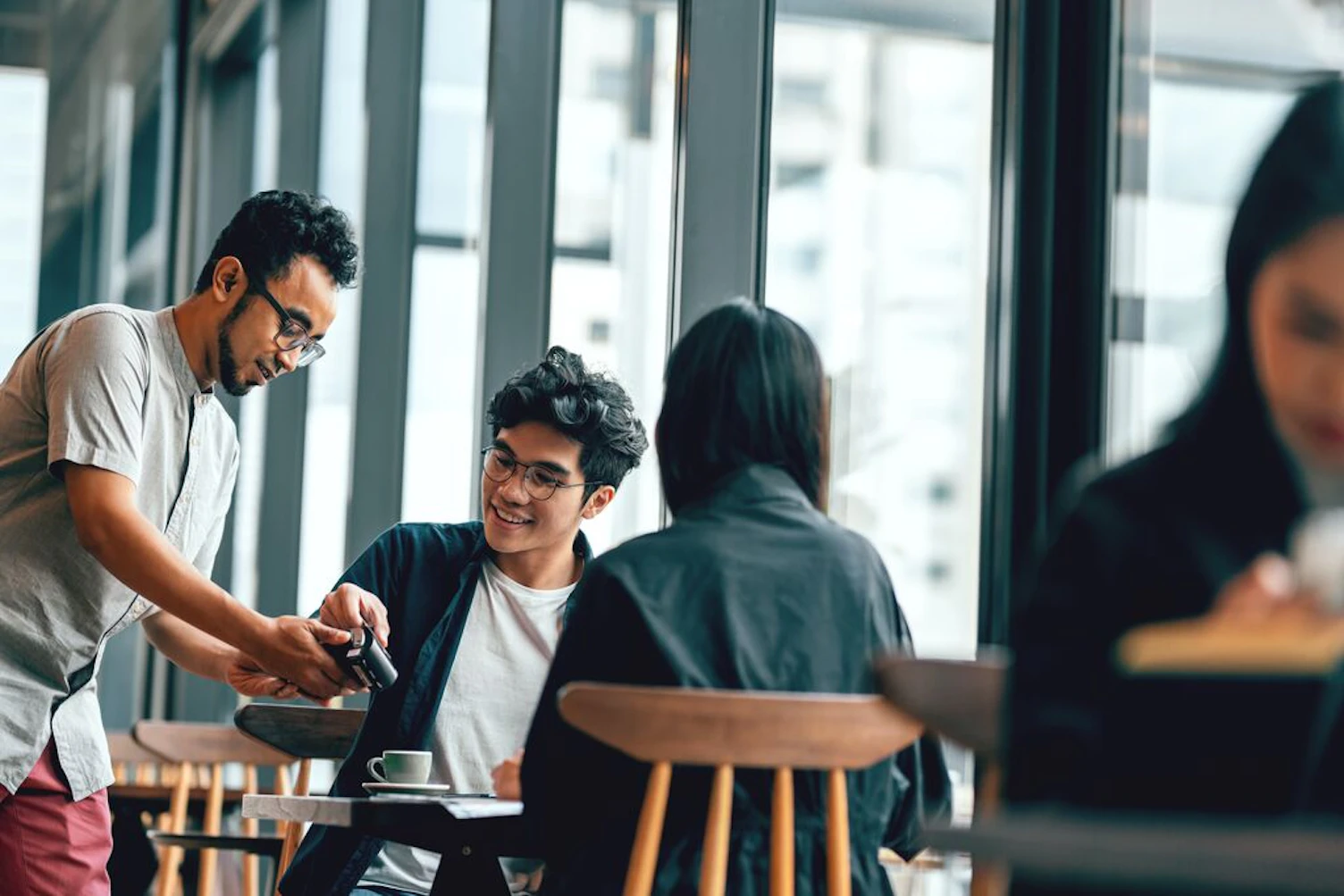 Couple in a Cafe Paying with Mobile Phone