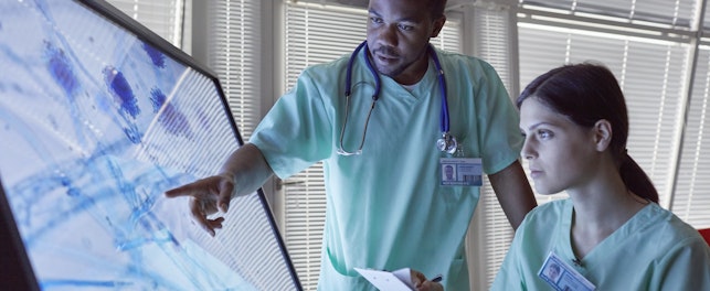 Doctors Examining Magnifying Microscope