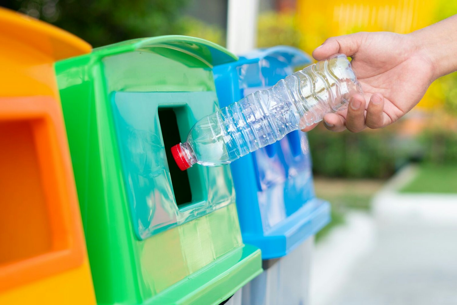 Hand Throwing Empty Plastic Bottle into the Recycling Trash