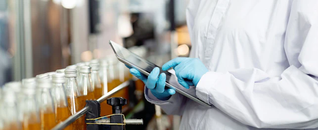 Hands of worker working with digital tablet check product on the conveyor belt in the beverage factory. Worker checking bottling line for processing. Inspection quality control