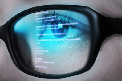 Programming Code of Computer Monitor Reflecting in Woman's Eyeglasses