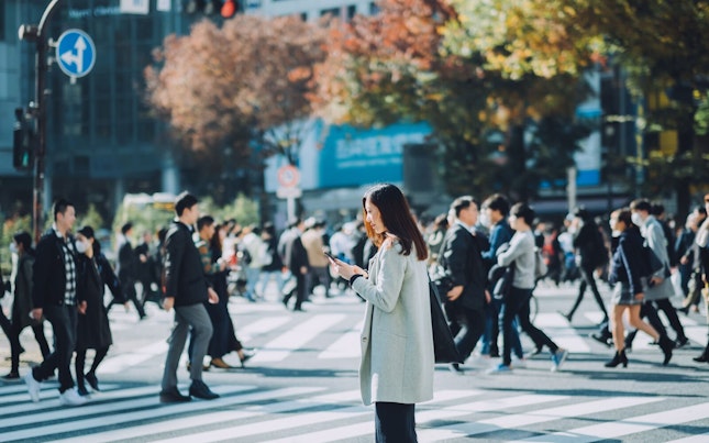 Woman Standing in a Crowd Looking at her Phone