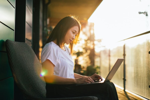 Woman Working on her Laptop on a Balcony