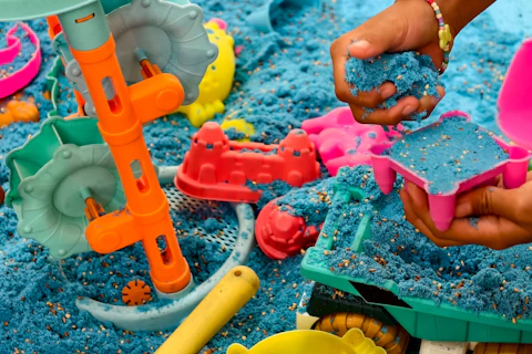 A childs hand plays with blue kinetic sand