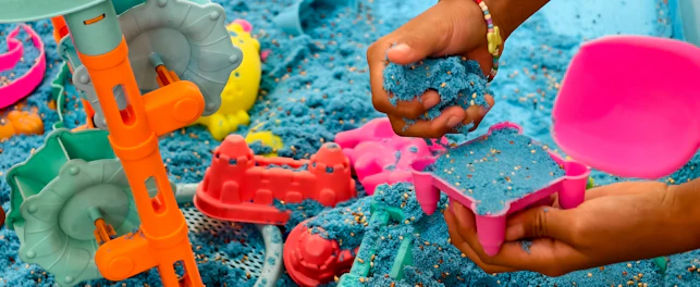 A childs hand plays with blue kinetic sand