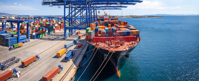 A large container cargo ship is beeing loaded and unloaded in a commercial dock