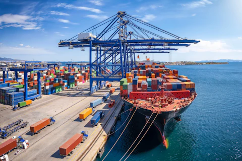 A large container cargo ship is beeing loaded and unloaded in a commercial dock