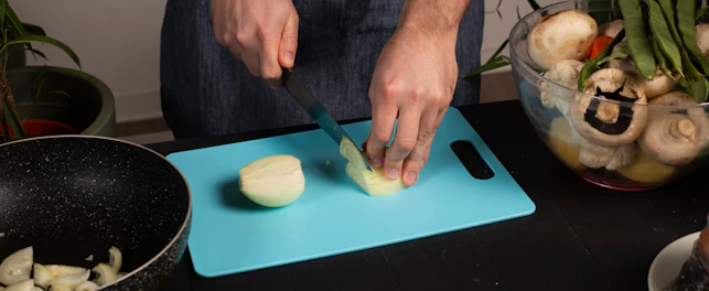 A man is cutting onions on a cutting board