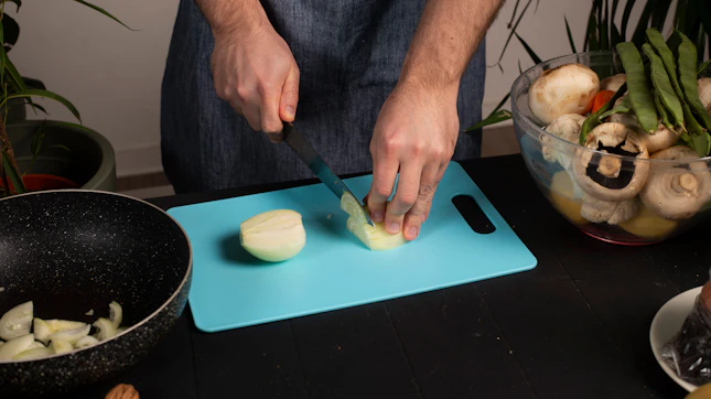 A man is cutting onions on a cutting board