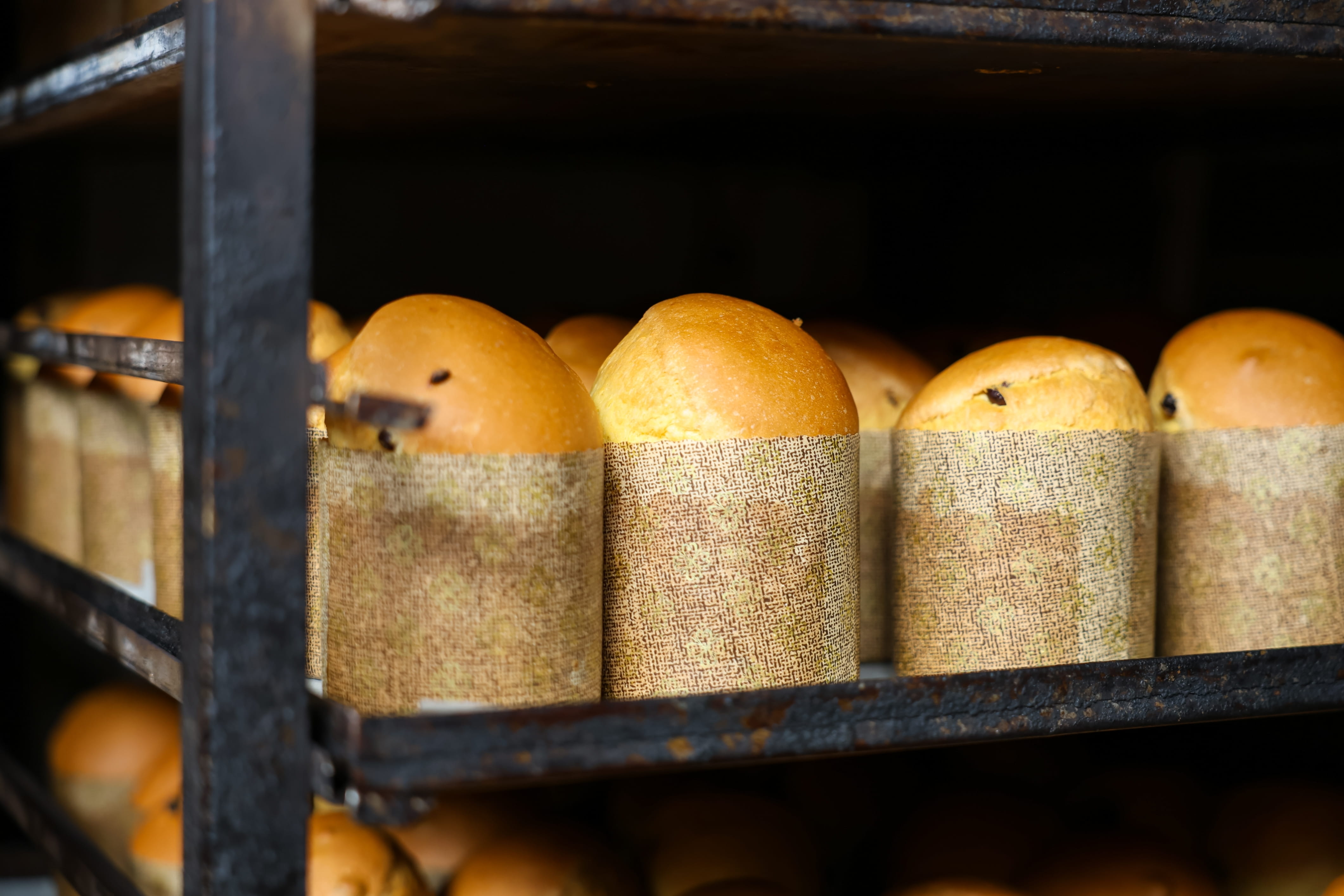 A rack of bread loaves with a paper wrapper