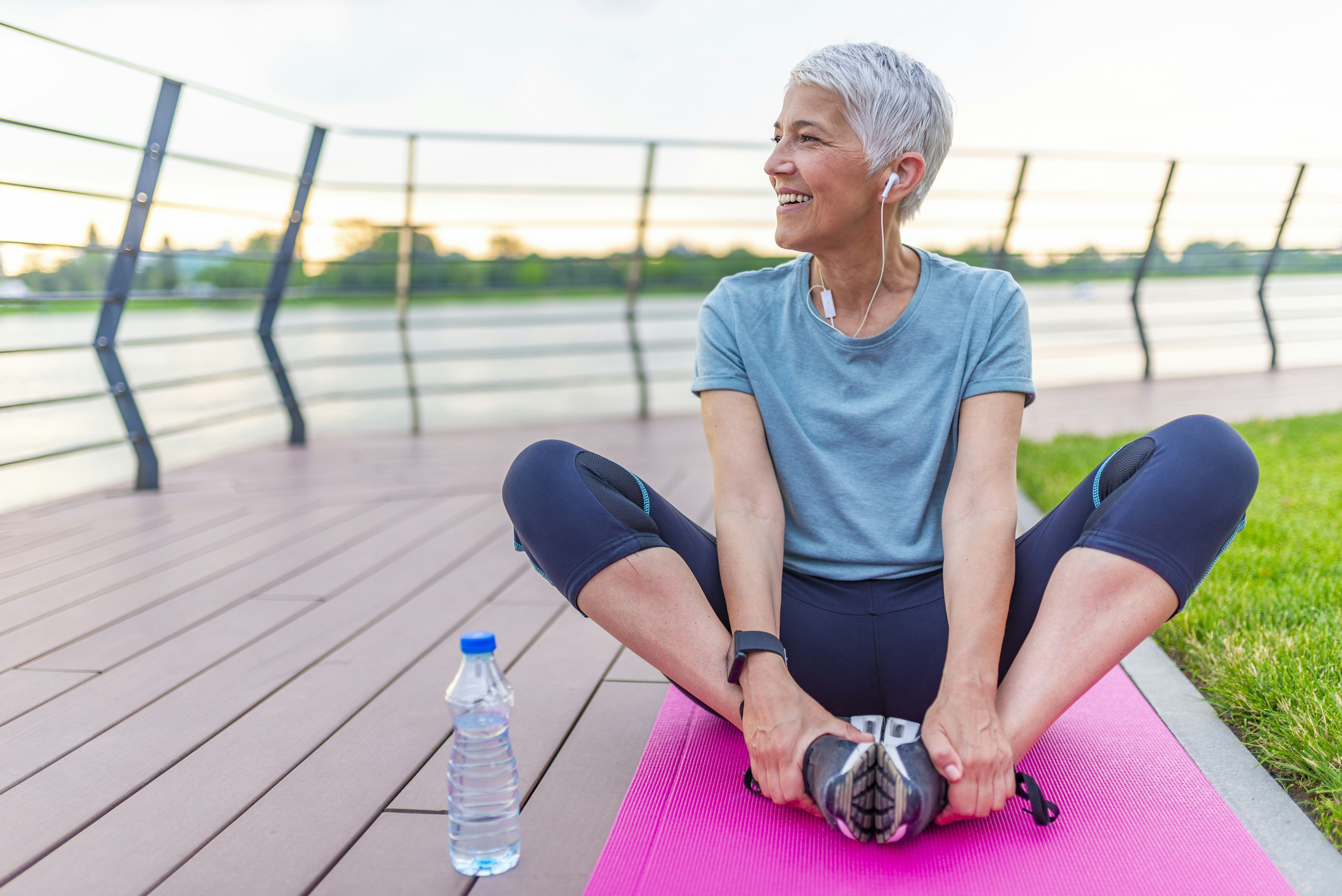 Athletic Mature Woman Sitting on Fitness Mat Outdoors