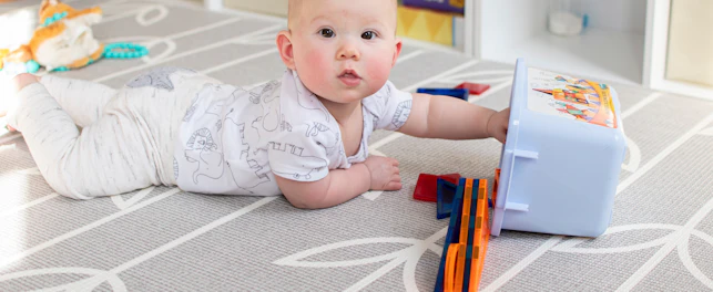 Baby laying on tummy playing with toys