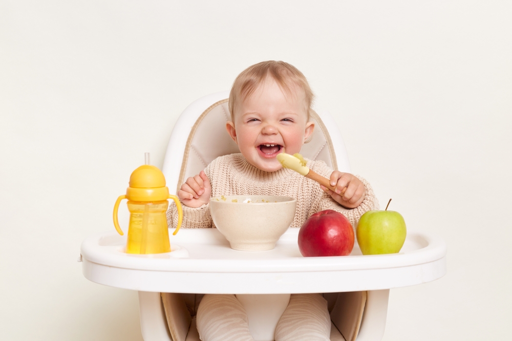 Baby wearing knitted sweater sitting in high chair