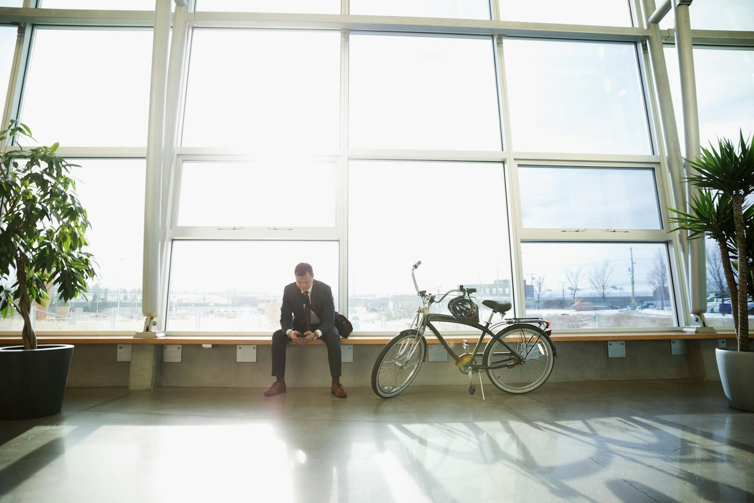 Businessman Sitting next to his Bicycle Waiting in Public Transit Area