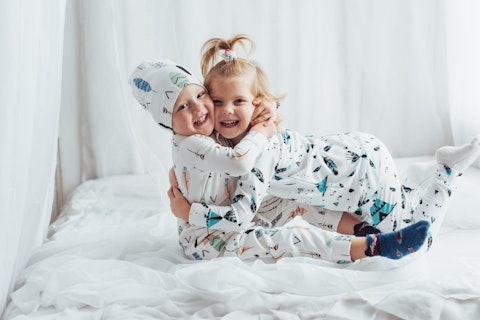 Children in soft warm pajamas playing in bed