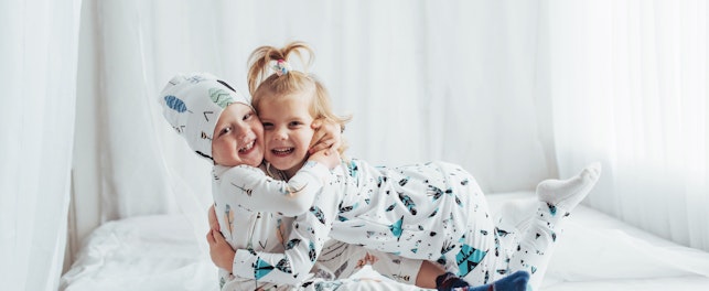Children in soft warm pajamas playing in bed