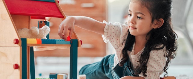 Girl, dollhouse and child play on floor, games and fantasy for brain development in home. Female person, toys and blocks on ground for entertainment, growth and toddler for education or learning