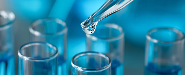 Dripping reagent into test tube against blurred background, closeup
