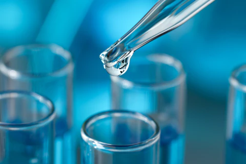 Dripping reagent into test tube against blurred background, closeup