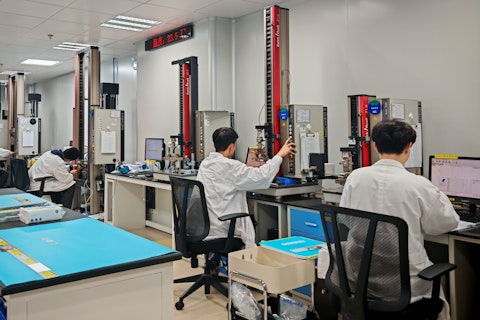 A laboratory setting with several people in lab coats seated at rubber material testing capability workstations.