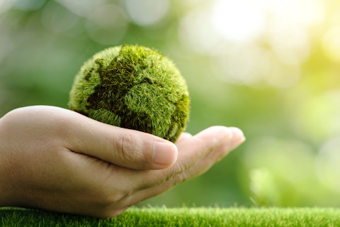 A hand gently holding a small, moss-covered globe, symbolizing care for nature, the Earth, and environmental sustainability.