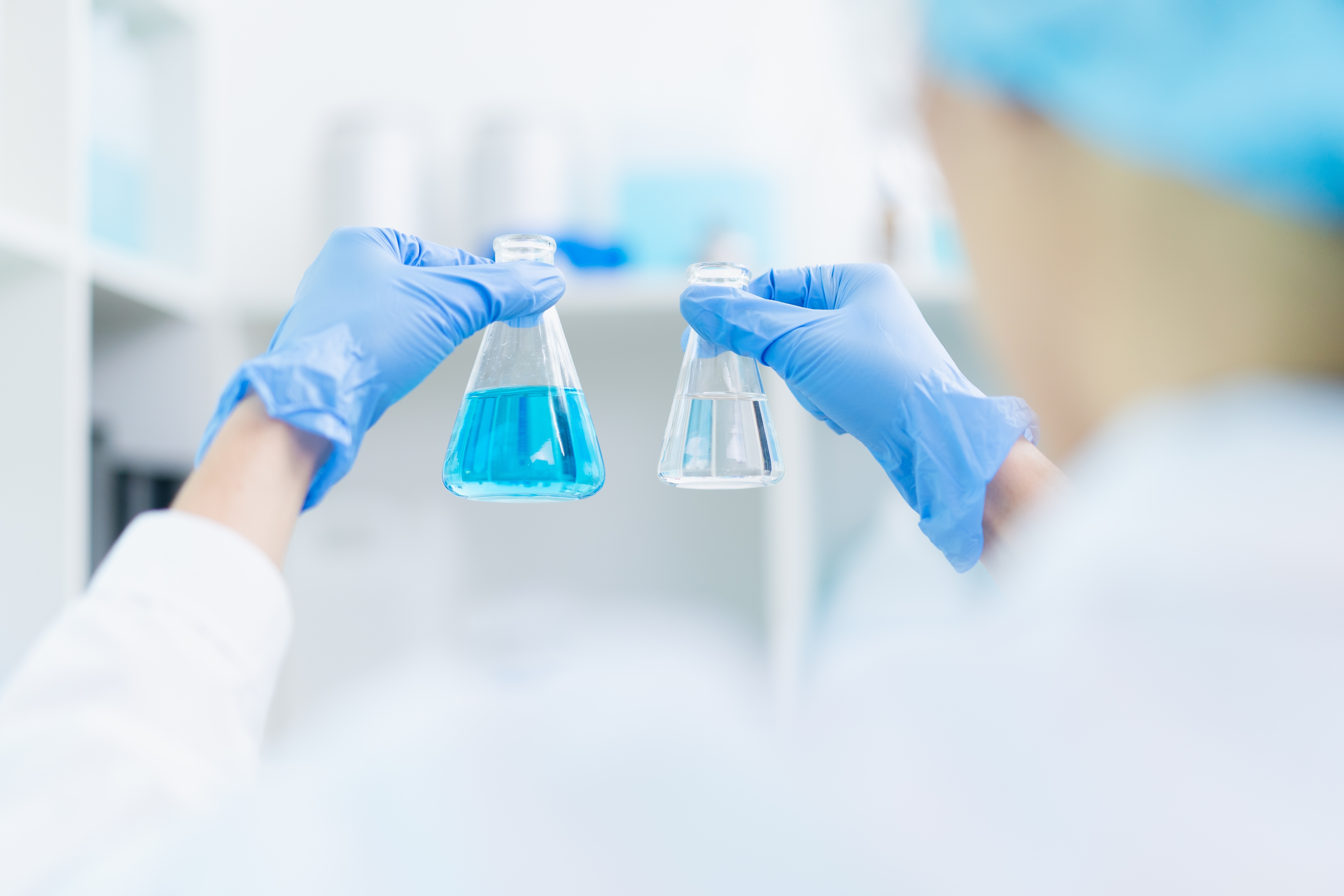 hand of scientist holding sample of chemical liquid in glassware comparing substance in laboratory