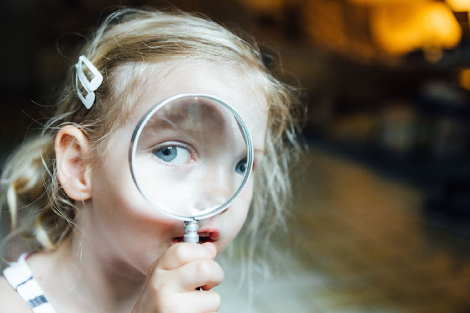 Niña mirando a través de la lupa