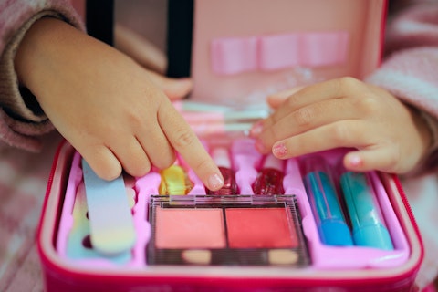 Little Girl with a Manicure Playing with a Toy Makeup Kit