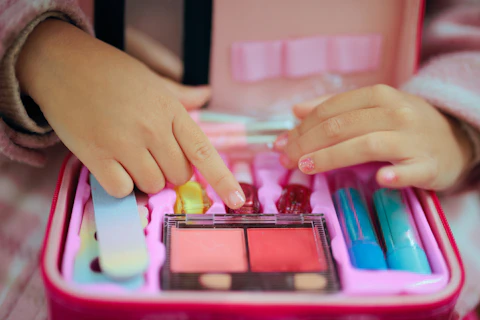 Little Girl with a Manicure Playing with a Toy Makeup Kit