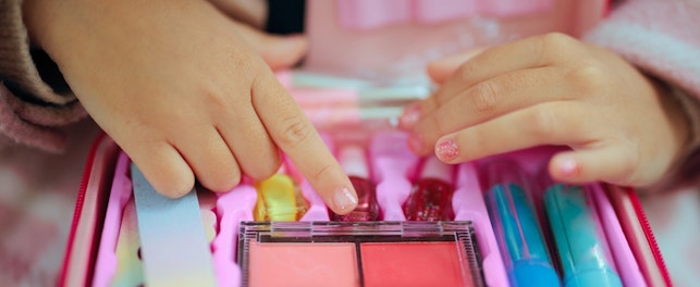 Little Girl with a Manicure Playing with a Toy Makeup Kit