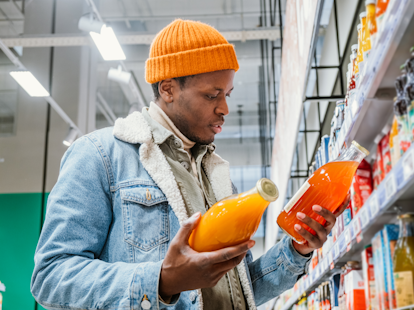 Man Reading Nutrition Label on Fresh Juice Bottle in Supermarket