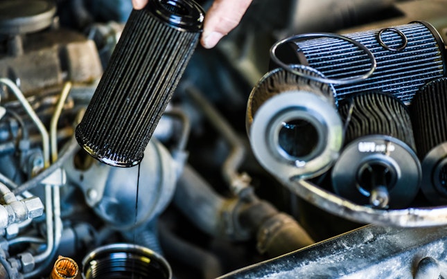 Mechanic changing old or used oil filter from car engine