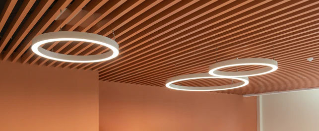 Plafond moderne avec des lamelles en bois et des luminaires LED circulaires