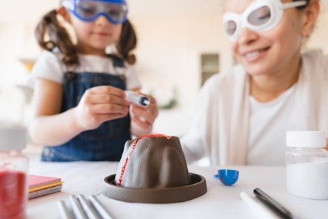 Mother and daughter in protective glasses watching a chemistry experiment
