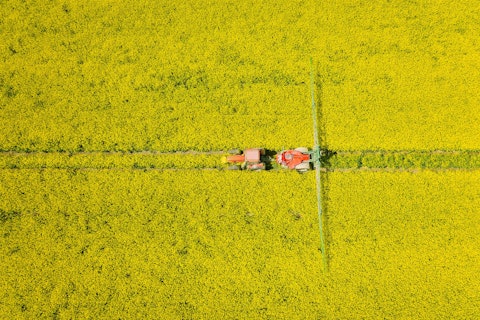 Orig Aerial View of Tractor Harvesting Field