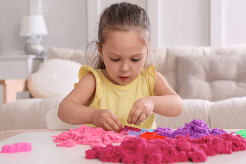 Petite fille jouant avec du sable cintique