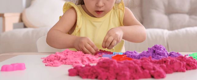 Petite fille jouant avec du sable cintique
