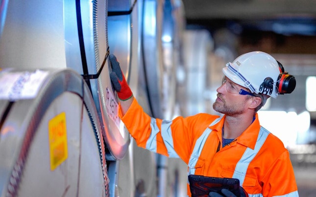 Quality Auditor Using Digital Tablet to Inspect Rows of Sheet Steel