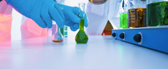 Scientists Mixing Colorful Liquid Chemicals in Flasks and Beakers