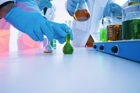 Scientists Mixing Colorful Liquid Chemicals in Flasks and Beakers