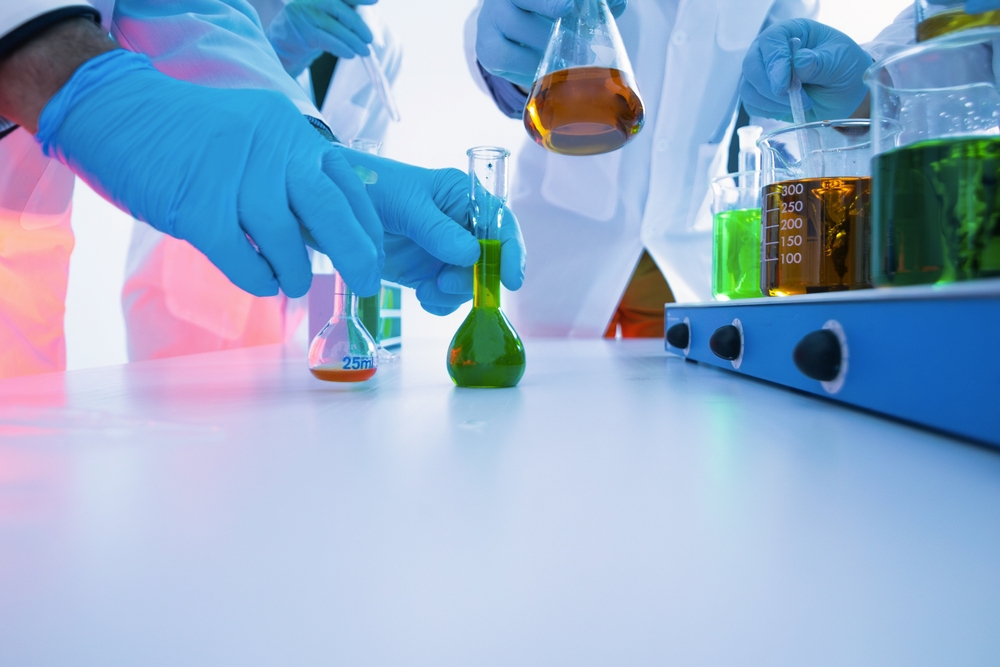 Scientists Mixing Colorful Liquid Chemicals in Flasks and Beakers