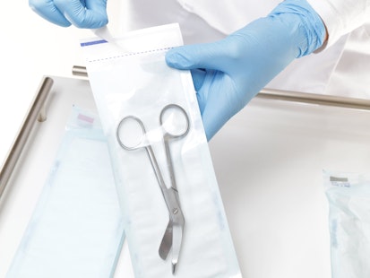 Emballage stérile pour dispositifs médicaux - SGS Dispositif médical stérilisé dans un emballage transparent, manipulé par une personne portant des gants bleus.