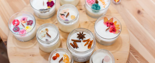 Variety of natural soy candles prepared during a workshop, decorated with dried flowers, herbs, and spices
